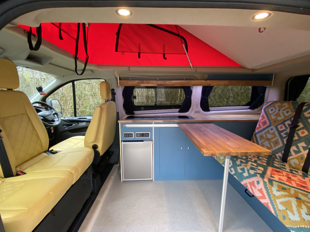 raleigh campervan interior design with mix of blue and wood effect finish and mix of cream and colourful aztec fabric upholstery